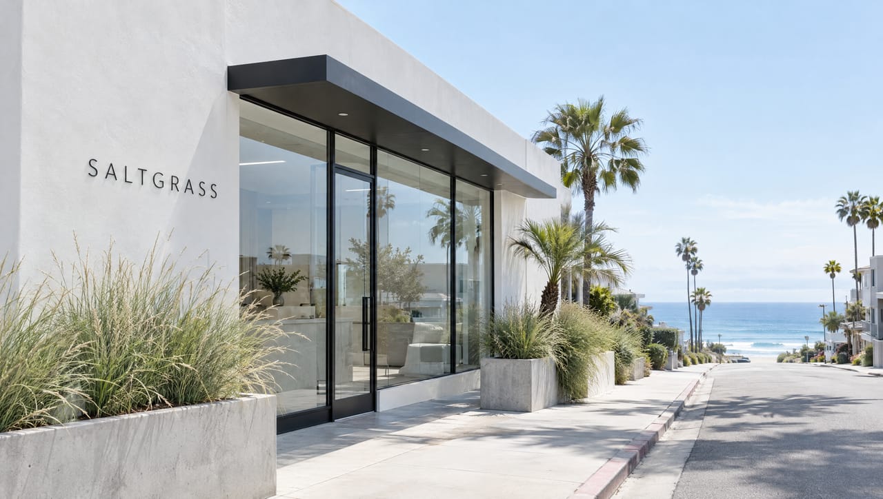 The white stucco Saltgrass clinic in Pacific Beach with saltgrass planters and the ocean at the end of the street