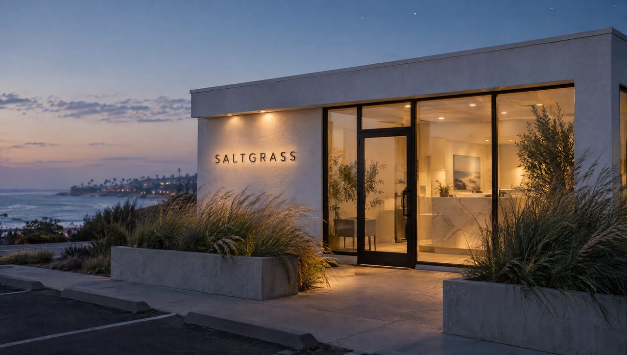 The Saltgrass clinic at blue hour with warm light through the glass and a lit sign